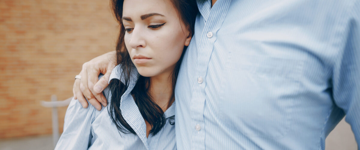 young beautiful couple husband in a shirt and a woman in a dress posing near the wall
